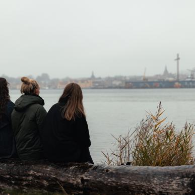 3 personer på stranden ser udover vandet